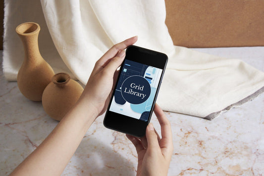 A person holds a smartphone showing the Luma Course app screen, with a cream fabric drape and two small tan ceramic vases in the background on a light marble surface.